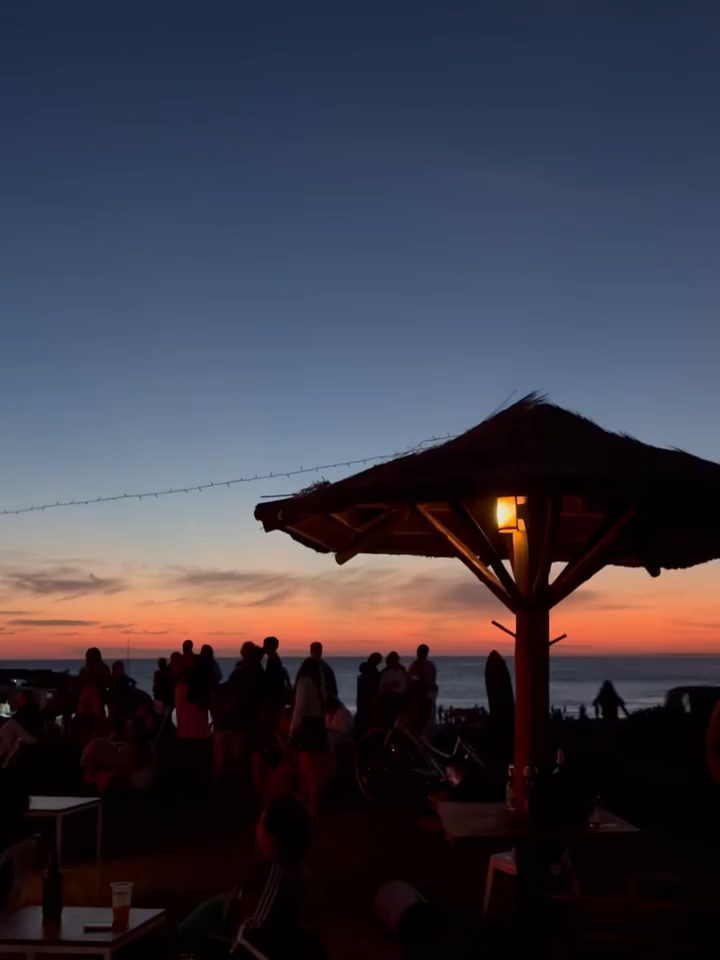 Carpa de playa y público al atardecer en Los Botes