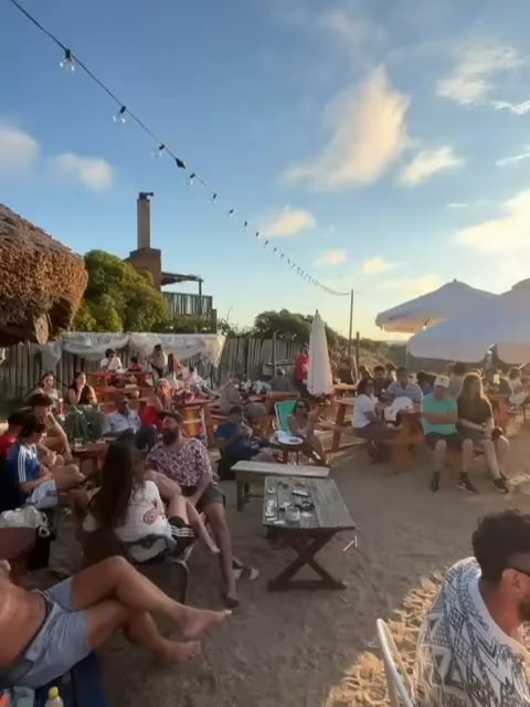 Público en las mesas durante una tarde en Playa Los Botes